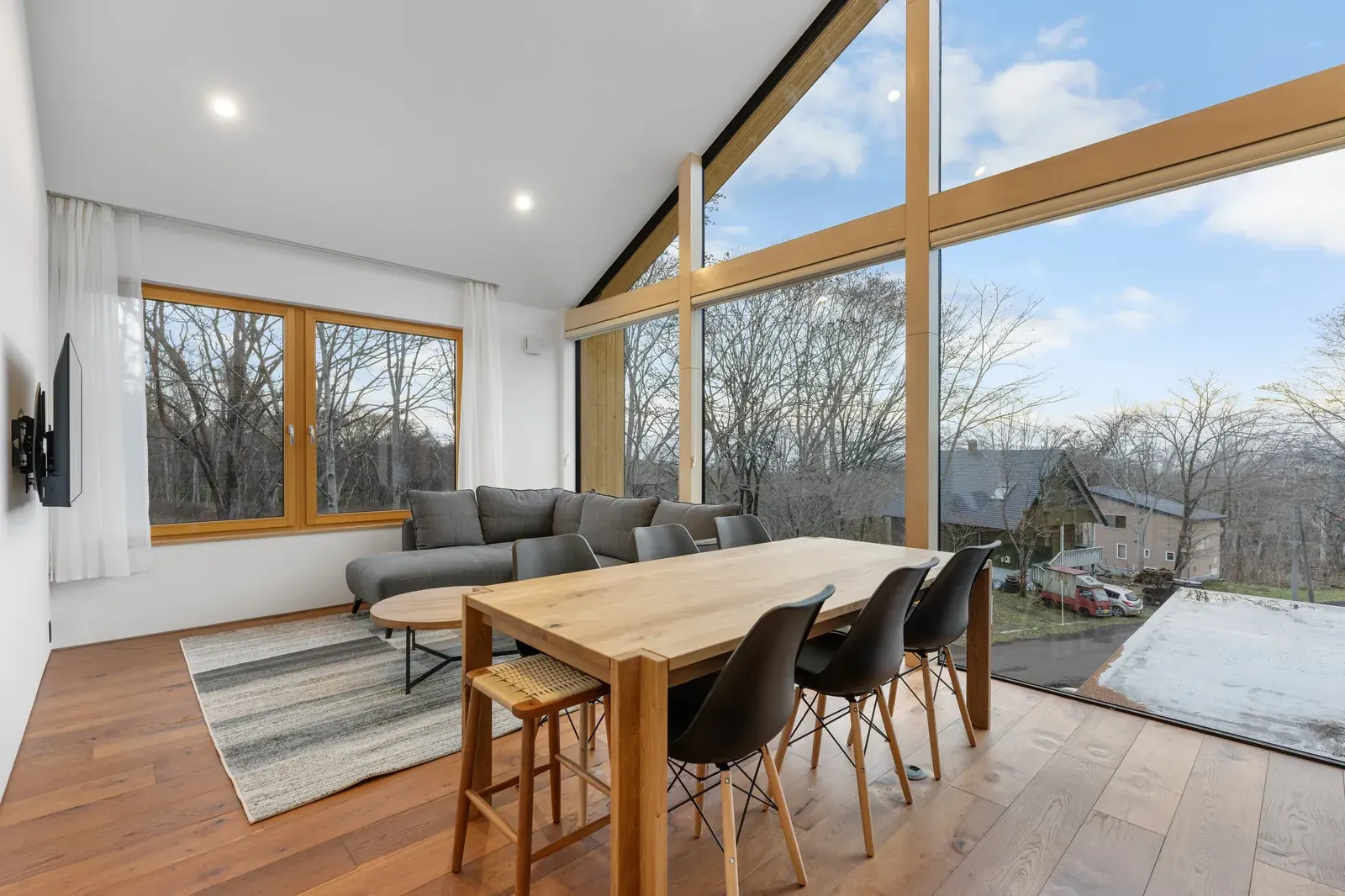 Living and dining room with a tall gabled window in a Niseko chalet