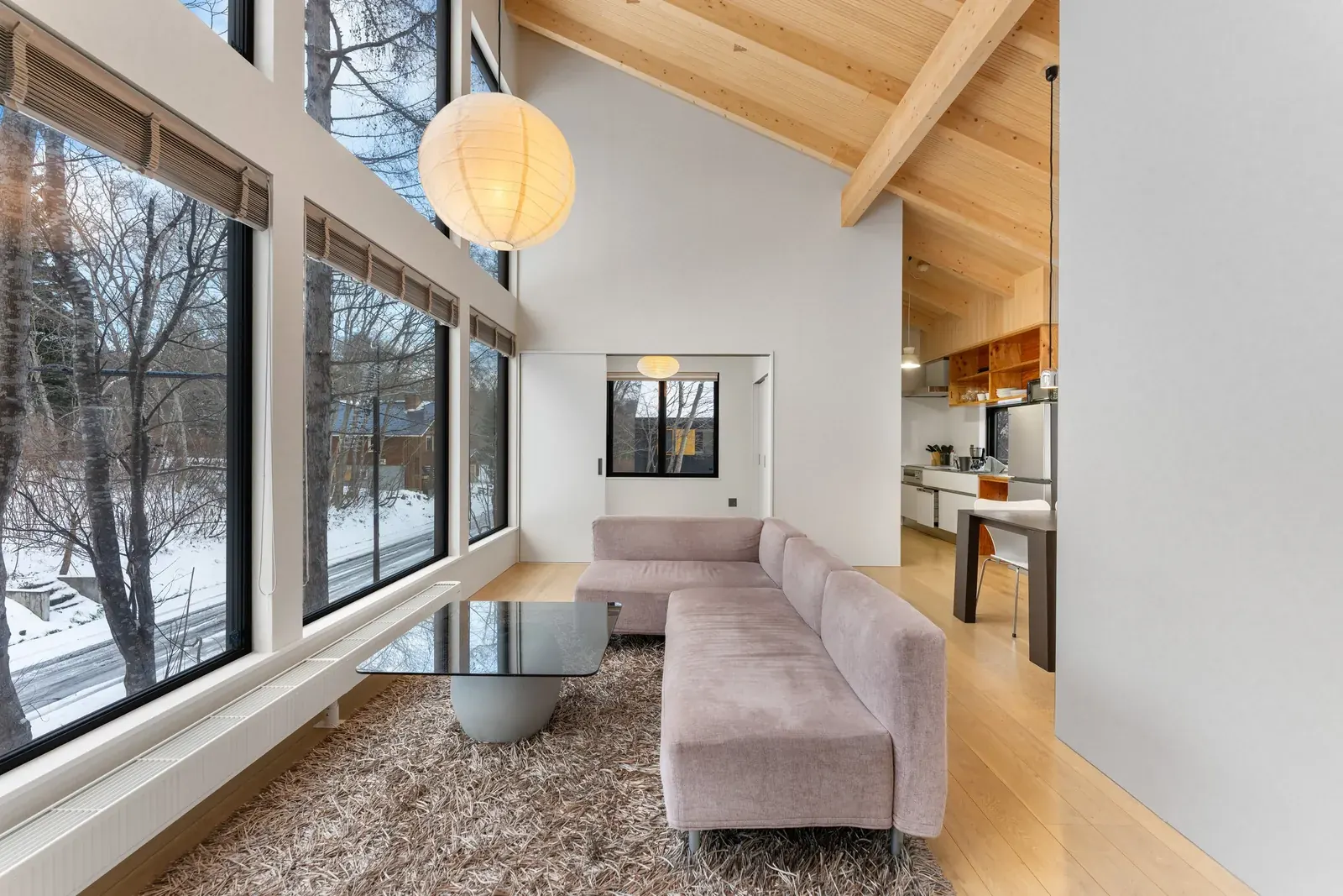 Lounge with floor-to-ceiling windows onto a snowy forest in Niseko