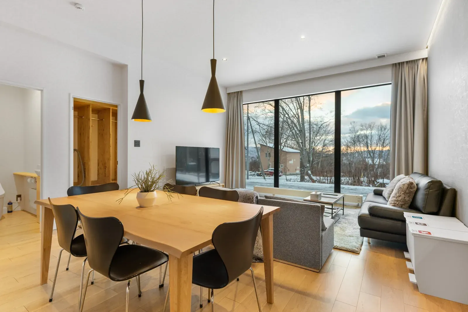 Living and dining room with a wide window onto the garden in a Niseko house