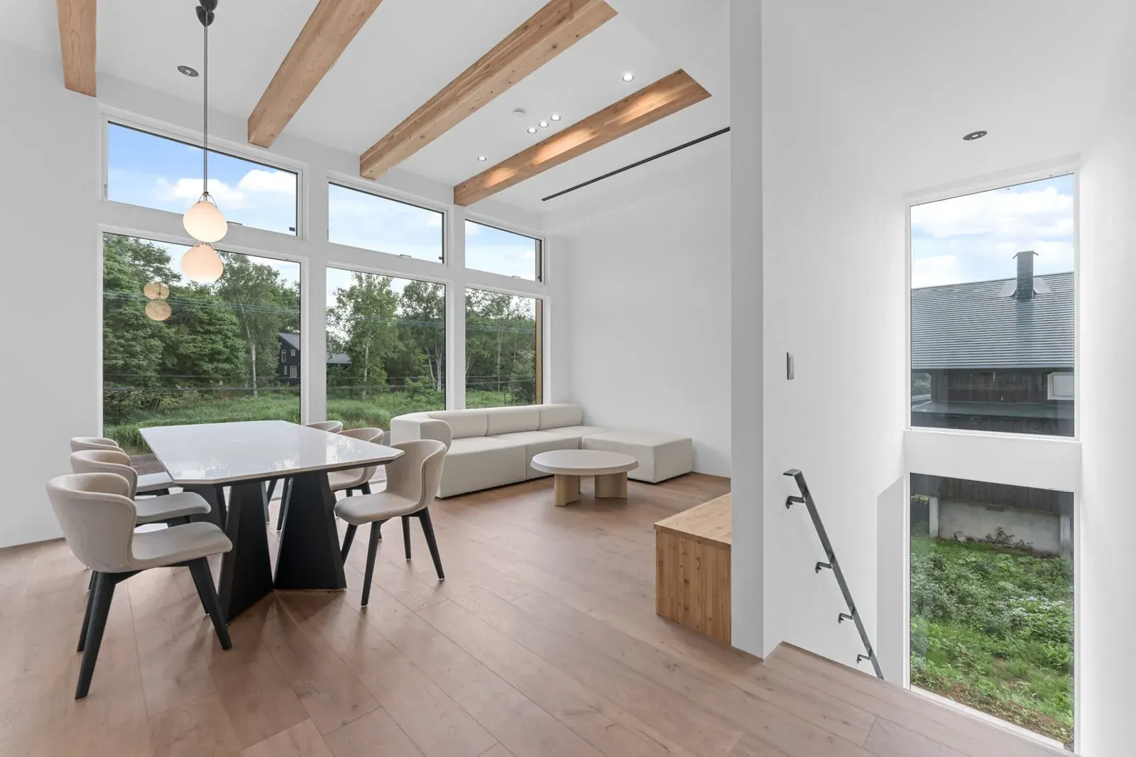 Living and dining room under exposed timber beams in a Niseko house